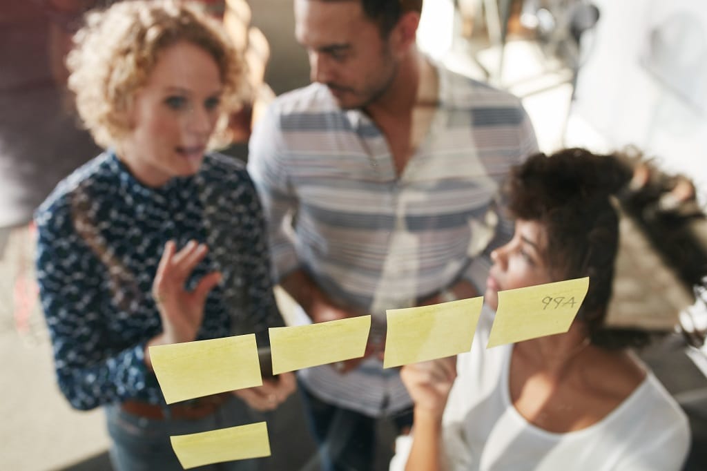 People in a meeting looking at sticky notes through glass