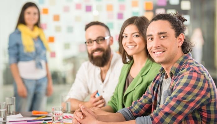 2 men and 2 women in a meeting looking directly at the viewer